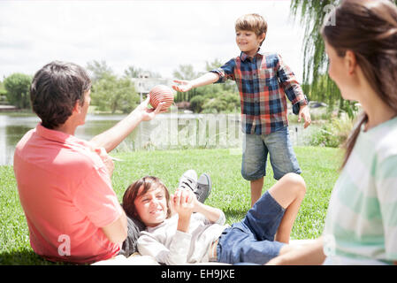 Father handing ball to young son Stock Photo