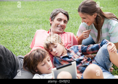 Family with two children spending afternoon at park, young boys using digital tablet Stock Photo