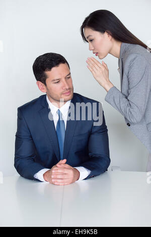 Assistant whispering in executive's ear Stock Photo