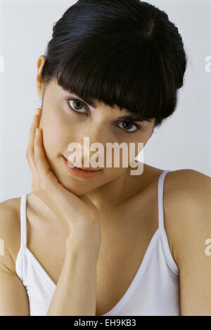 Dark haired young woman with hand under chin, portrait Stock Photo