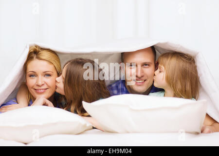 two little girls kissing their parents on cheek Stock Photo