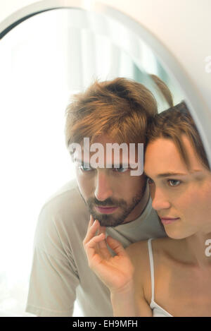 Couple looking into mirror together, wife caressing husand's bearded chin Stock Photo