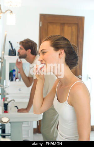 Woman brushing teeth, husband shaving Stock Photo