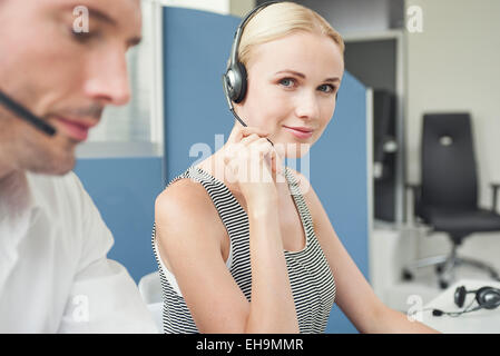 Woman wearing phone headset at desk Stock Photo
