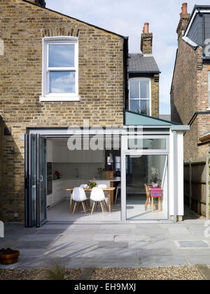 Patio, rear facade and view of kitchen through open glass doors, residential house, UK Stock Photo