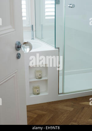 View through open door detail of inset shelves with candles on the side of the bath in Chesilton Road home, UK Stock Photo