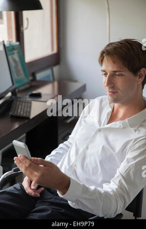 Businessman holding smartphone in office Stock Photo