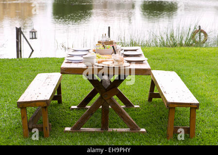 Picnic table set for meal outdoors Stock Photo