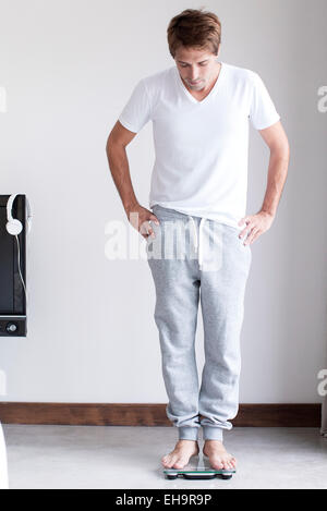 Man weighing self on bathroom scale Stock Photo