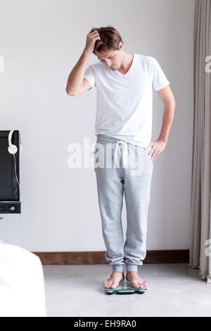 Man weighing self on bathroom scale Stock Photo