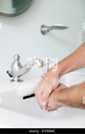 Man washing hands in bathroom sink Stock Photo