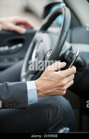 Businessman text messaging while driving, cropped Stock Photo