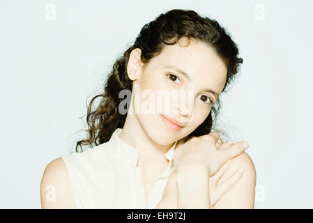 Young woman touching shoulder, smiling at camera, portrait Stock Photo