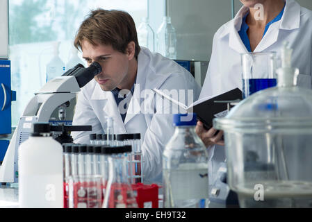 Scientist looking through microscope in laboratory Stock Photo