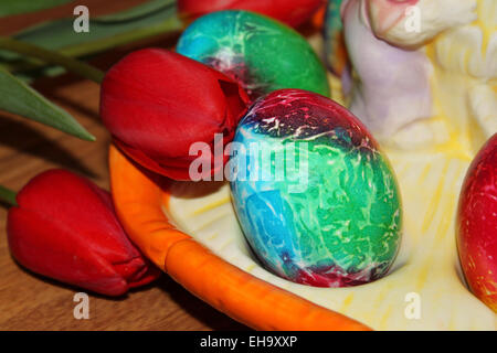 Colored Easter eggs on a plate and red tulips Stock Photo
