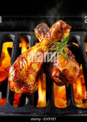 Flame grilled barbecue chicken legs cooking on a bbq over hot charcoal Stock Photo