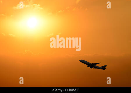 Airplane Taking Off Silhouetted Against a Sunset. Stock Photo