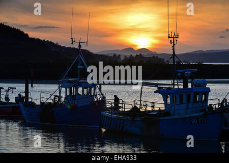 Donegal, Ireland. 10th March, 2015. Weather: A man stands on the ‘Ros Eireann’ fishing boat as the sun sets over Lough Swilly at Fahan, County Donegal. Widespread showers are forecast for Donegal on Wednesday. Credit:  George Sweeney/Alamy Live News Stock Photo