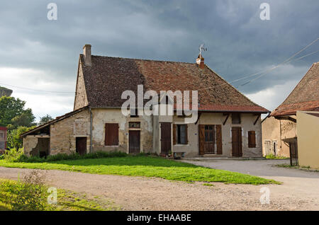 Dark clouds mass behind an old farmhouse in Gigny-sûr-Saône, Burgundy, France. Stock Photo