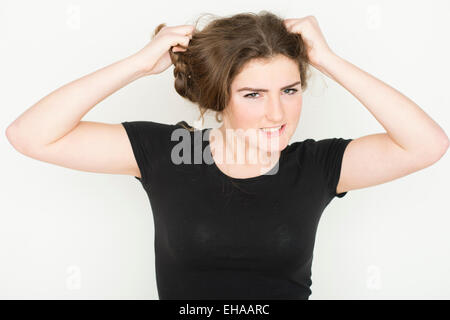 A moody 13 14 year old teenage girl tearing at her hair UK Stock Photo