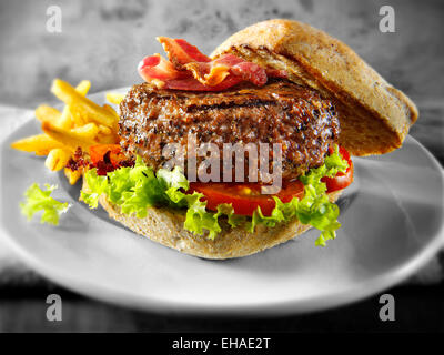 Beef burger with bacon in a  bun with salad and fries chips Stock Photo