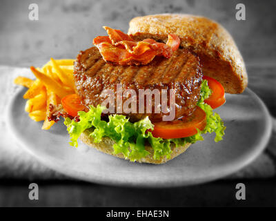 Beef burger with bacon in a  bun with salad and fries chips Stock Photo