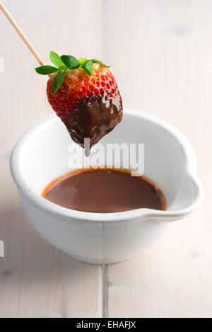 Strawberry in a skewer dipped in melted chocolate. Stock Photo