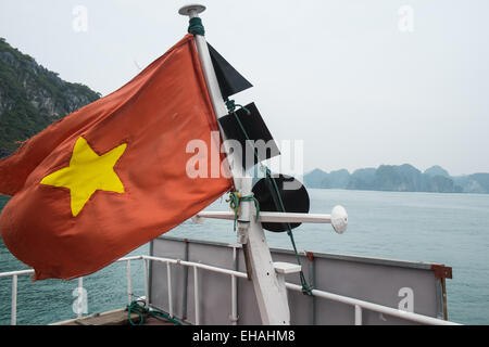 Vietnamese flag atop of tourist boat amongst limestone karst in Cat Ba National Park,Ha long,Halong Bay, Vietnam Stock Photo