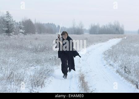 running samurai wearing a kimono in a winter field dressed in black, frost Stock Photo