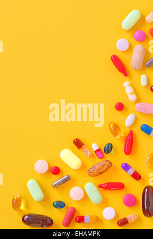 Many colorful pills isolated on yellow background Stock Photo