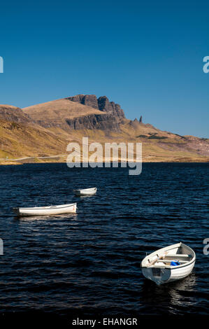 The Storr and the Old Man of Storr under a deep blue sky with small white rowing boats on Loch Fada in the foreground. Isle of S Stock Photo