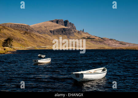 The Storr and the Old Man of Storr under a deep blue sky with small white rowing boats on Loch Fada in the foreground. Isle of S Stock Photo