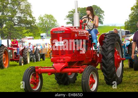 Young woman on McCormick Farmall BM classic tractor. Skelton Show Cumbria, England, UK. Stock Photo