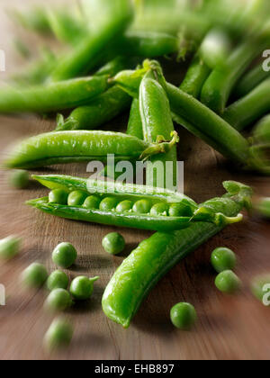 Food still life of fresh picked garden peas and pea in pods  on a rustic table in a kitchen being prepared