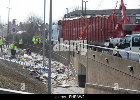 London, UK. 11th March, 2015. Truck overturned spewing rubbish into the subway path at Sun in the Sands roundabout, Blackheath. Emergency services clearing up waste after the lorry flipped onto the side of the Sun In The Sands Roundabout at around 7.15am. Stock Photo