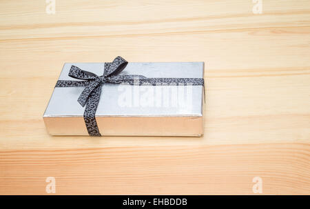 silver gift box with bow on wooden table Stock Photo