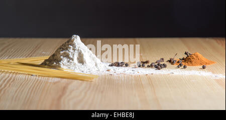 still life: hill of flour, spices and spaghetti on the wooden table Stock Photo