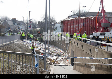 London, UK. 11th March, 2015. Truck overturned spewing rubbish into the subway path at Sun in the Sands roundabout, Blackheath. Emergency services clearing up waste after the lorry flipped onto the side of the Sun In The Sands Roundabout at around 7.15am. Stock Photo