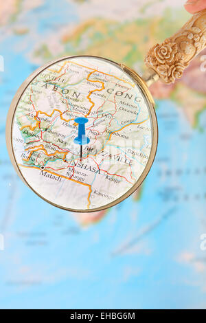 Blue tack on map of Africa with magnifying glass looking in on Kinshasa, Democratic Republic of Congo Stock Photo