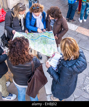 Group of five girls, young women, tourists looking at a tourist map of Seville Spain pointing and discussing directions Stock Photo