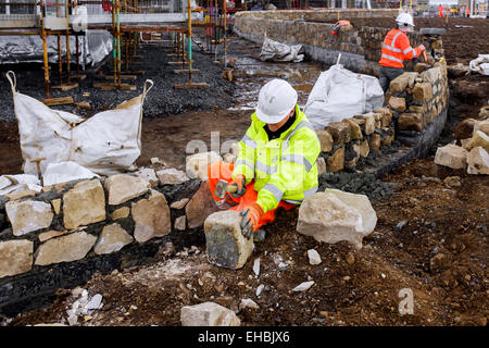 Master mason building a decorative perimeter wall of bloom sandstone on a new build housing estate, Troon, Ayrshire, Scotland Stock Photo