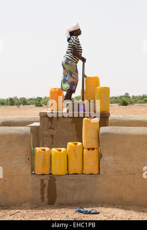 Djagourou vilage, Tera, west Niger; a woman uses the village foot pump to fill jerry-cans with water. Stock Photo