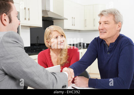 Mature Couple Shaking Hands With Financial Advisor At Home Stock Photo