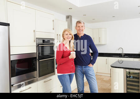 Mature Couple Standing In Beautiful Fitted Kitchen Together Stock Photo