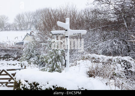 Snow covered country and signpost at Challacombe on Exmoor in Devon England pointing to Barnstaple to left and Exford to right Stock Photo