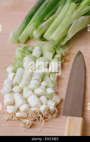 chopped green spring onions on wooden cutting board Stock Photo