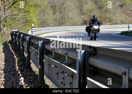 Motorcycle rider on country road with crash barrier protection Germany Europe Stock Photo