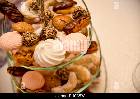 Cookies, marshmallows, eclair, chocolate balls with nuts placed on glass support Stock Photo