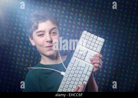 smiling teenage boy with computer keyboard and letters salad as background Stock Photo