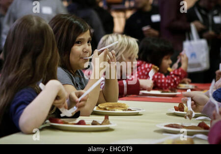 Vancouver, Canada. 11th Mar, 2015. Children enjoy their food during the Pancake Breakfast event in Vancouver, Canada, March 11, 2015. About 450 kids under poverty were served with breakfast during the 22nd annual Pancake Breakfast event organized by KidSafe Project Society. The event aimed to raise the awareness of the children poverty issue. © Liang Sen/Xinhua/Alamy Live News
